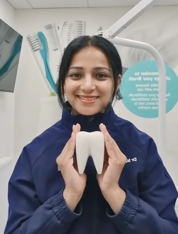 Dr Nayana Sawant smiling and holding a model tooth