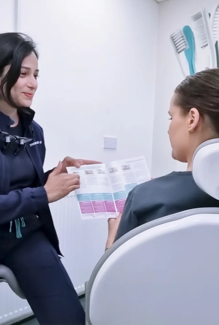 Dr Sawant explaining a treatment leaflet to a patient in the dental chair